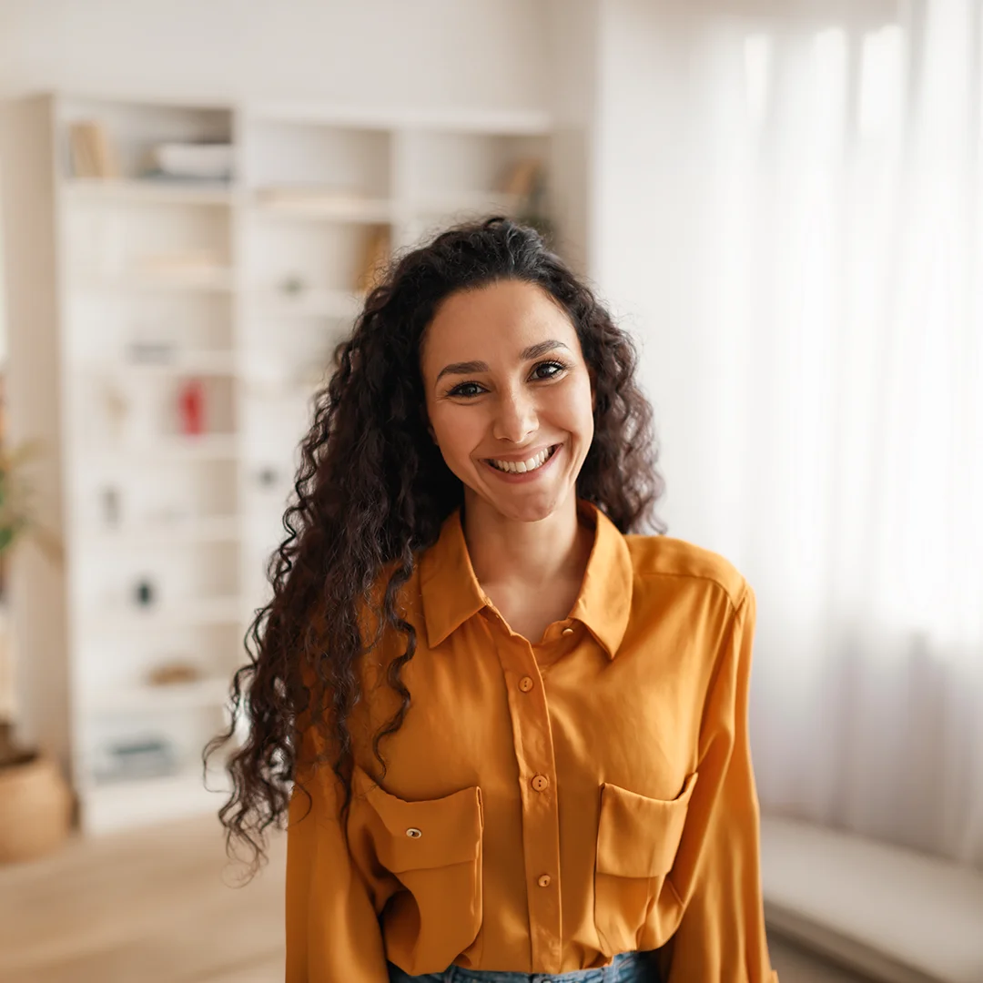 Woman with curly hair smiling in a bright home office setting